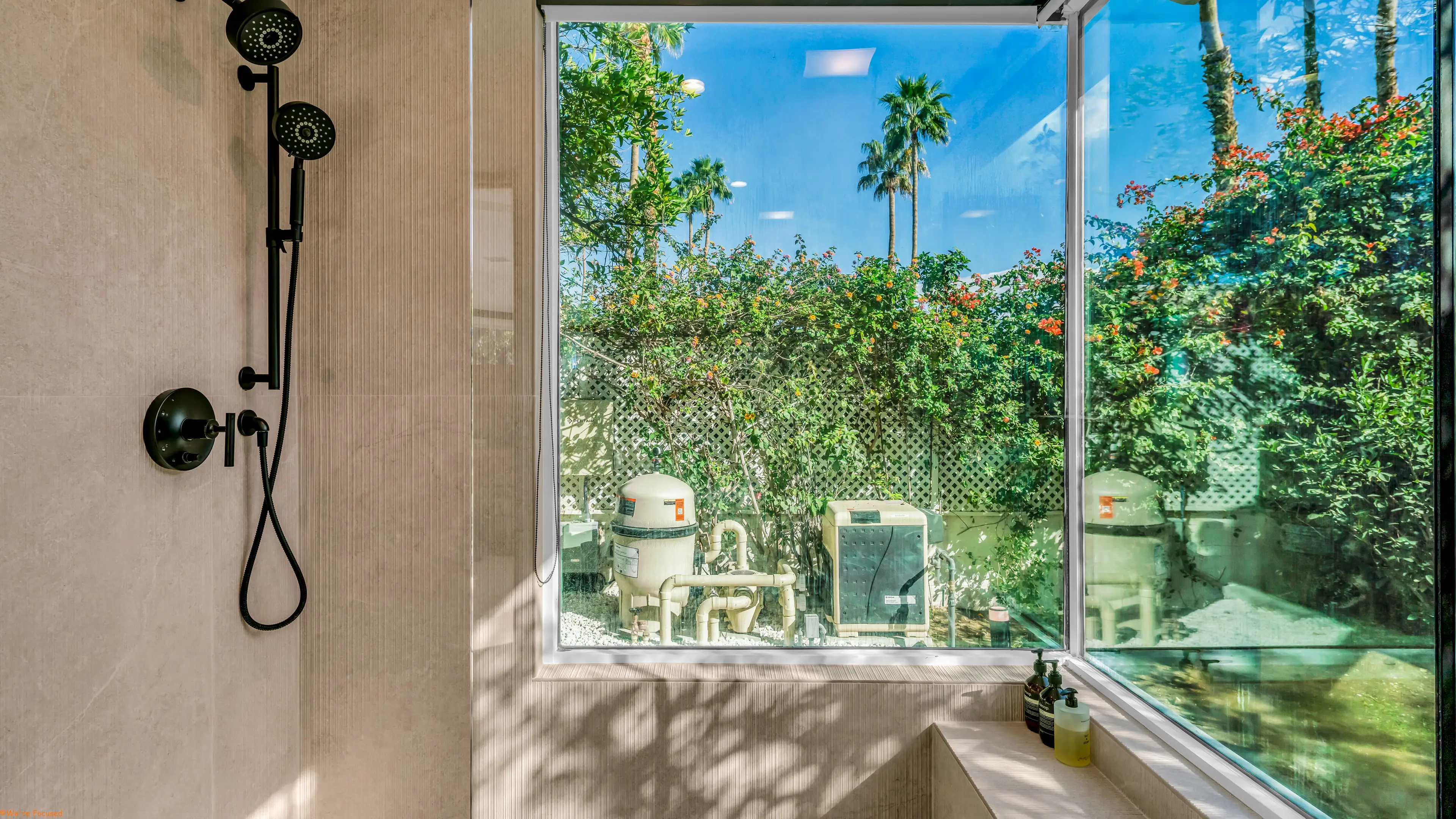 A shower corner window looking into the planting beyond the wall.