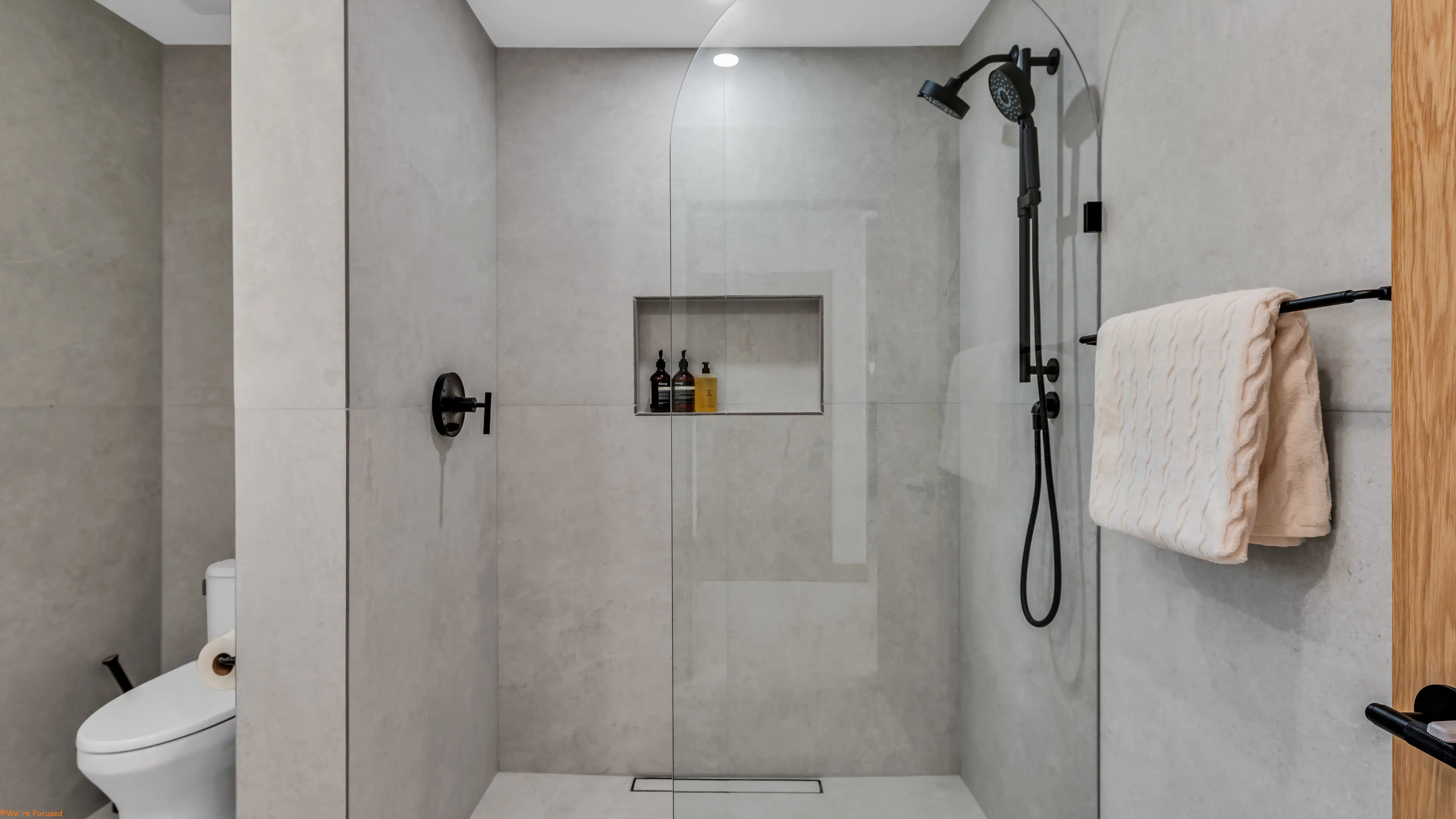 A walk in shower in pale stone with a built in niche.