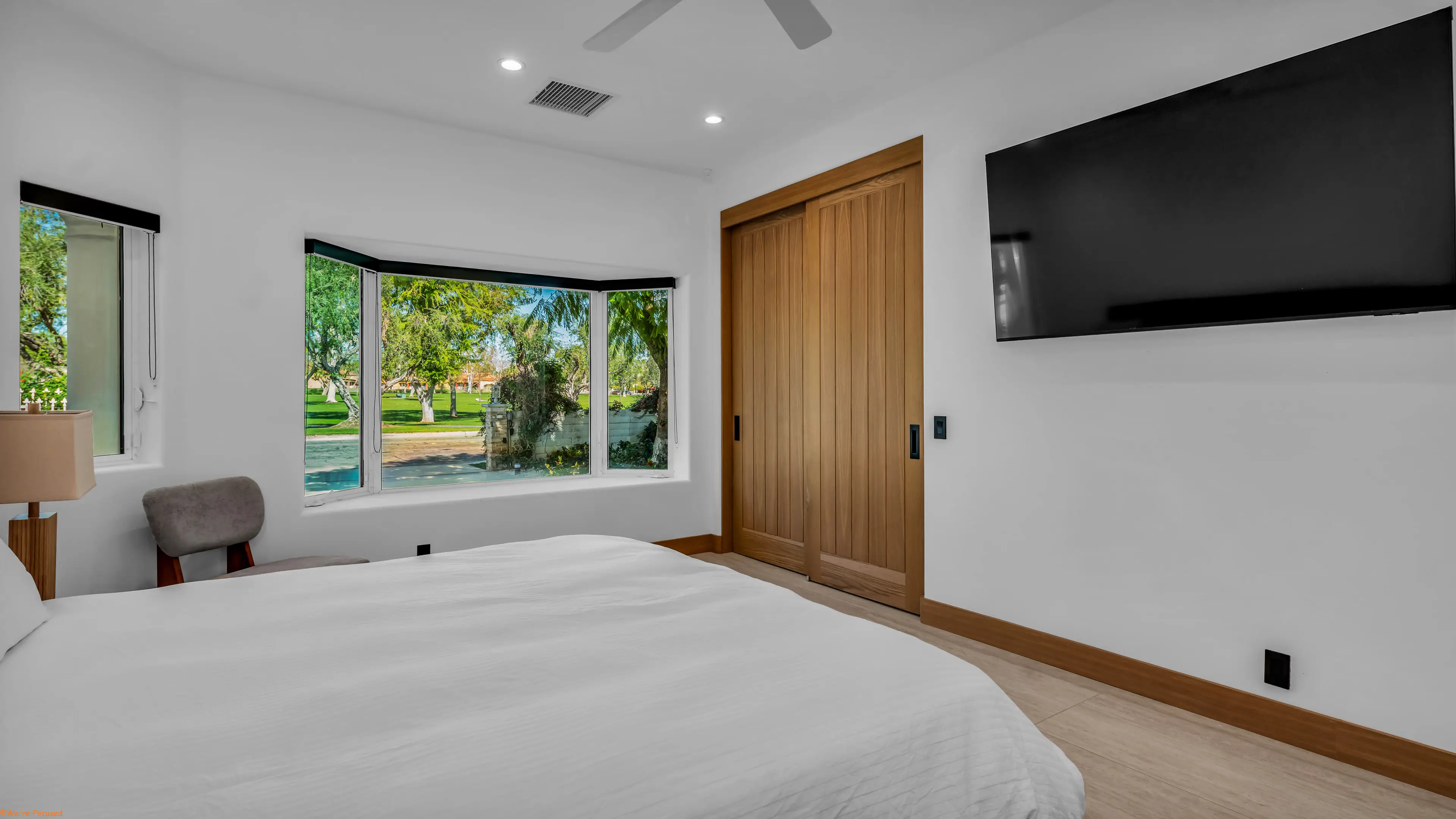 Bedroom with a bay window, wardrobe doors in oak and a wall mounted television.