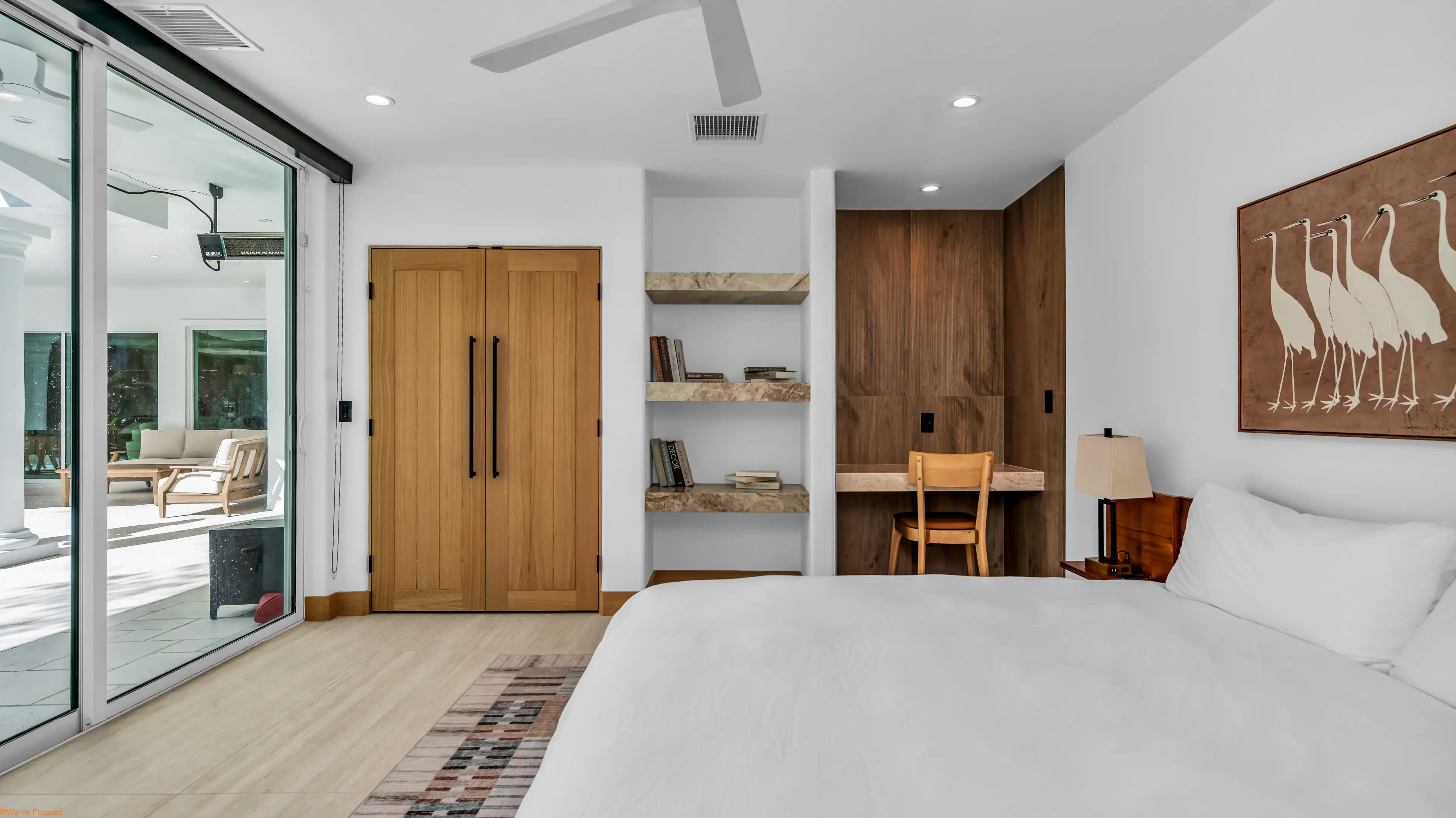 Bedroom with built in shelving, a writing desk and glass doors onto the terrace.