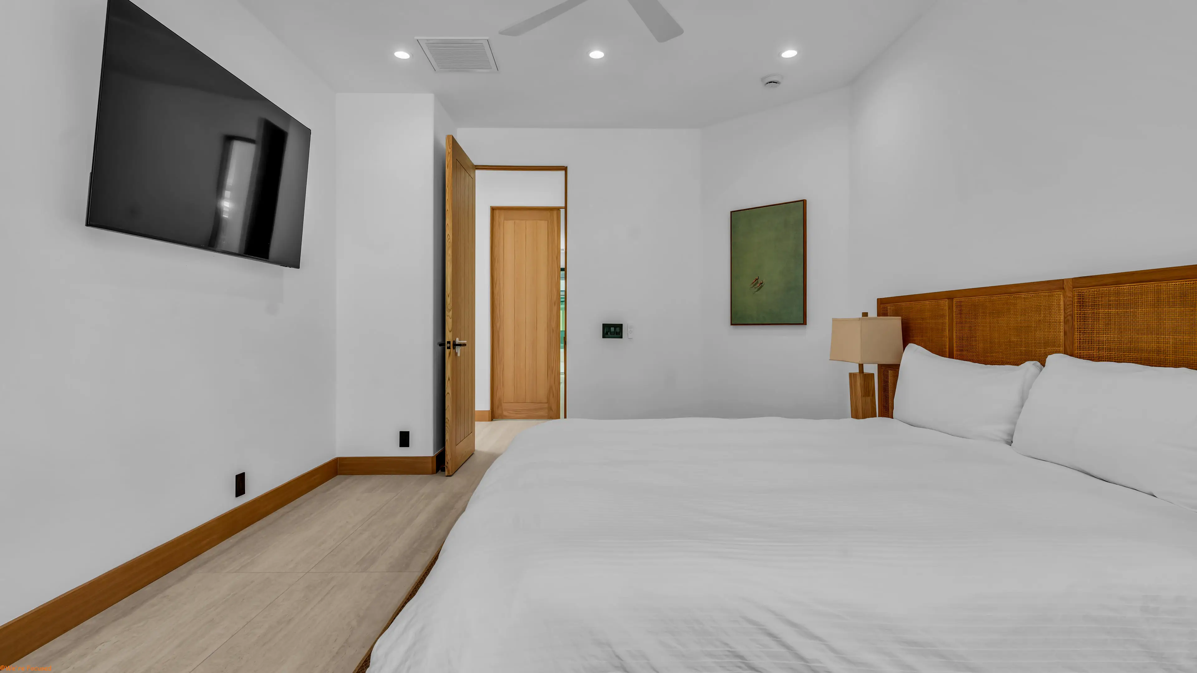 Bedroom with a cane headboard, a bedside lamp and a door to the hallway.