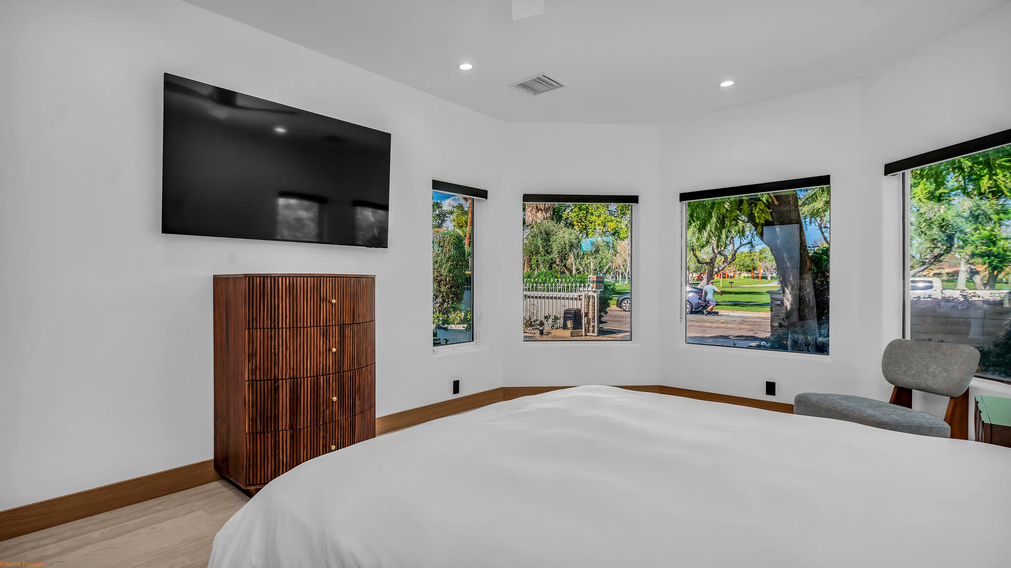 Bedroom with a dark wood chest and bay windows onto the garden.