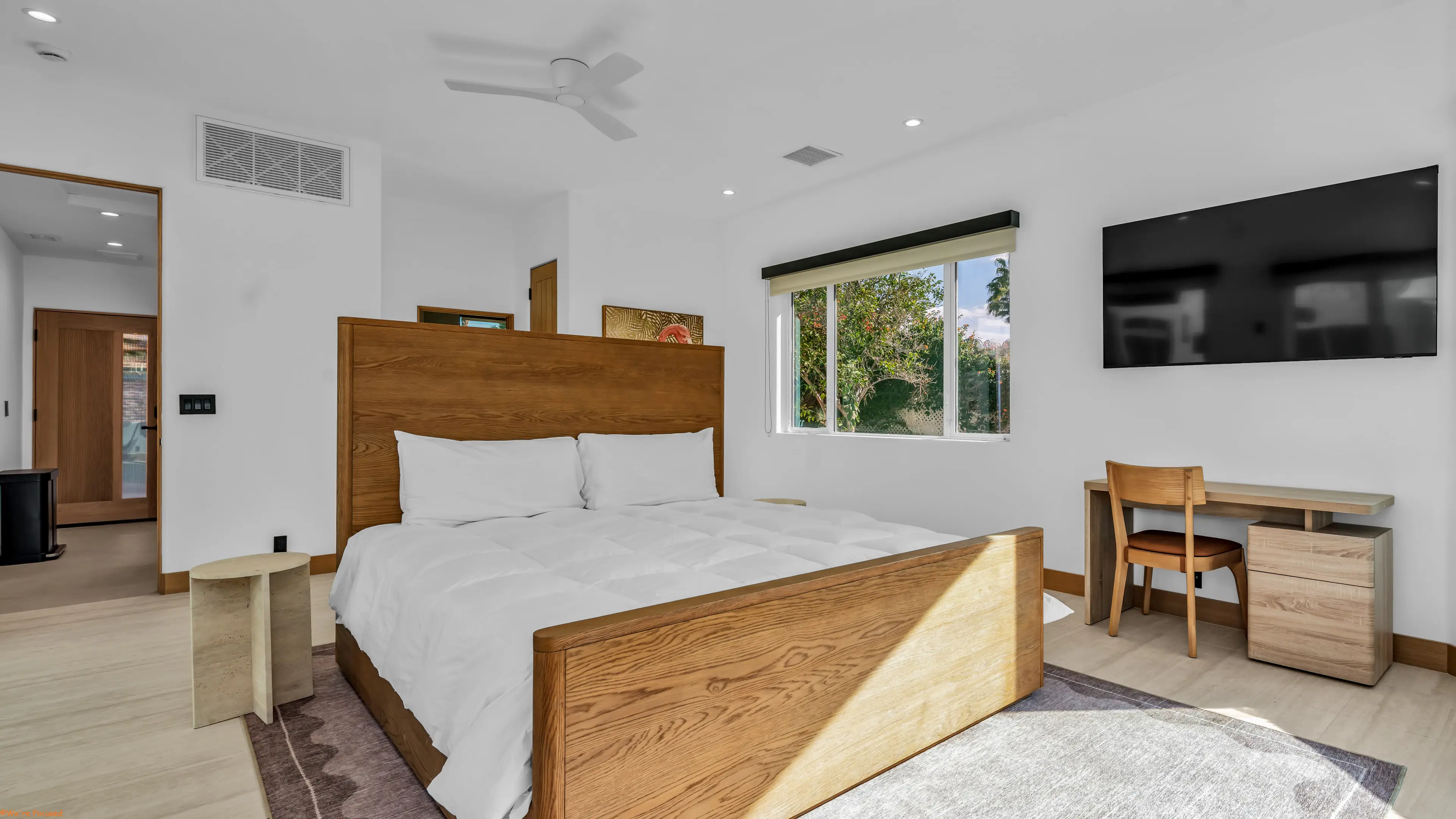 Bedroom with an oak bed frame, a desk and a window onto the garden.