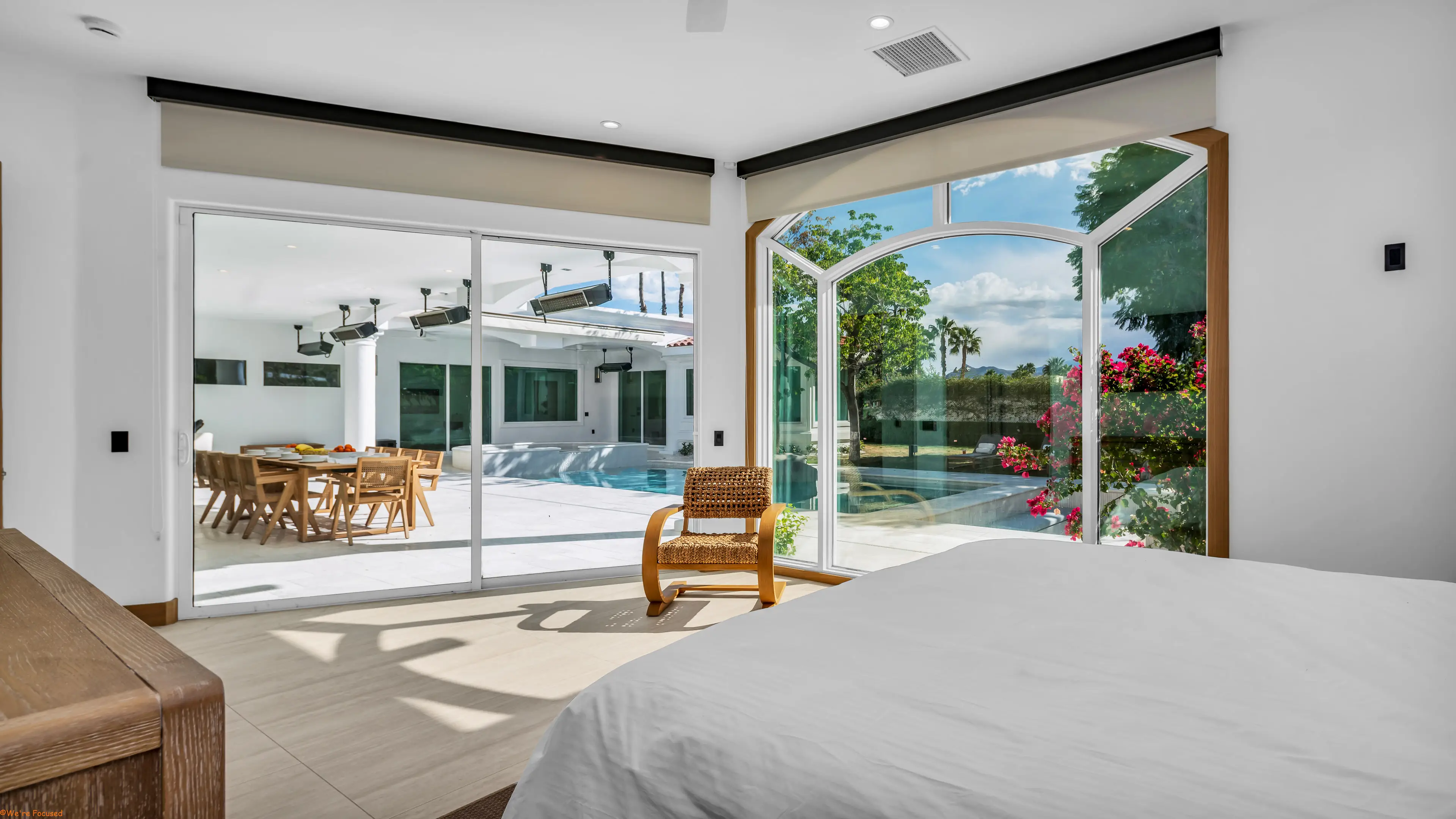 Bedroom looking through open glass doors to the terrace, the pool and the garden.