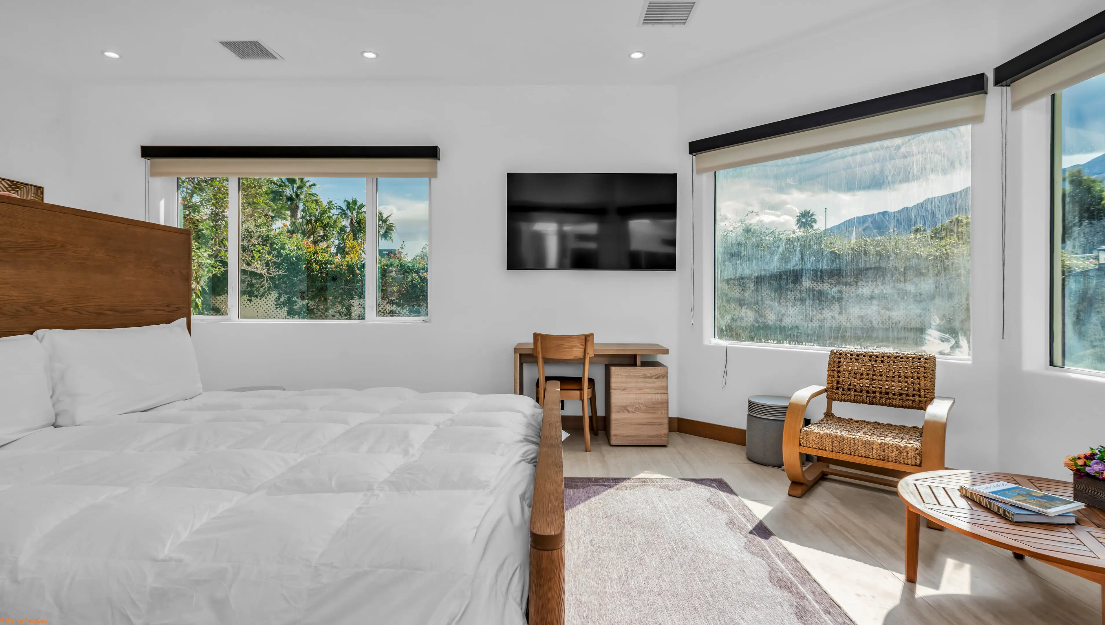Bedroom with a tall wood headboard, a window seat and a writing table.