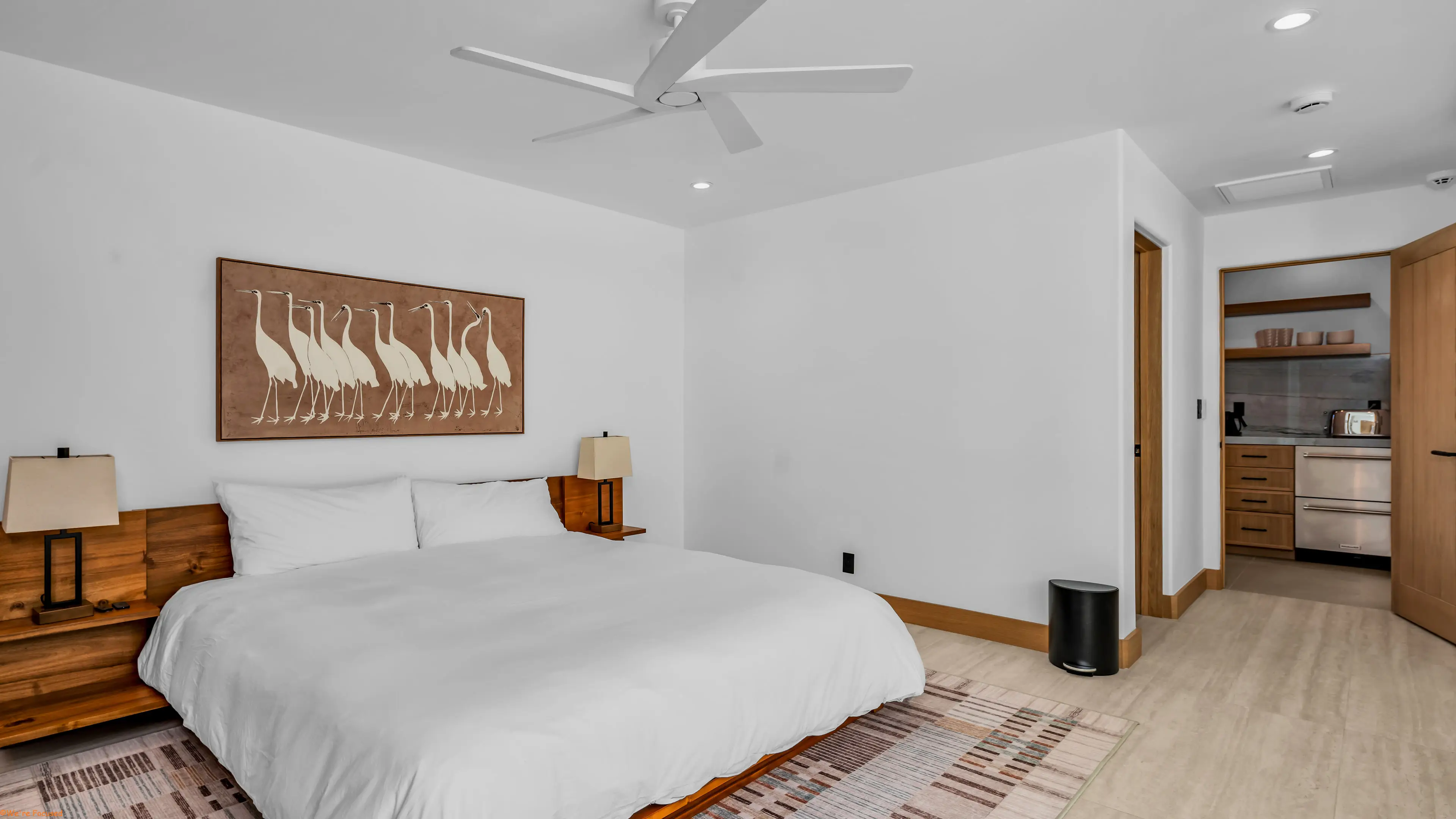 Bedroom with a wood bed, artwork above and a door through to the bathroom.