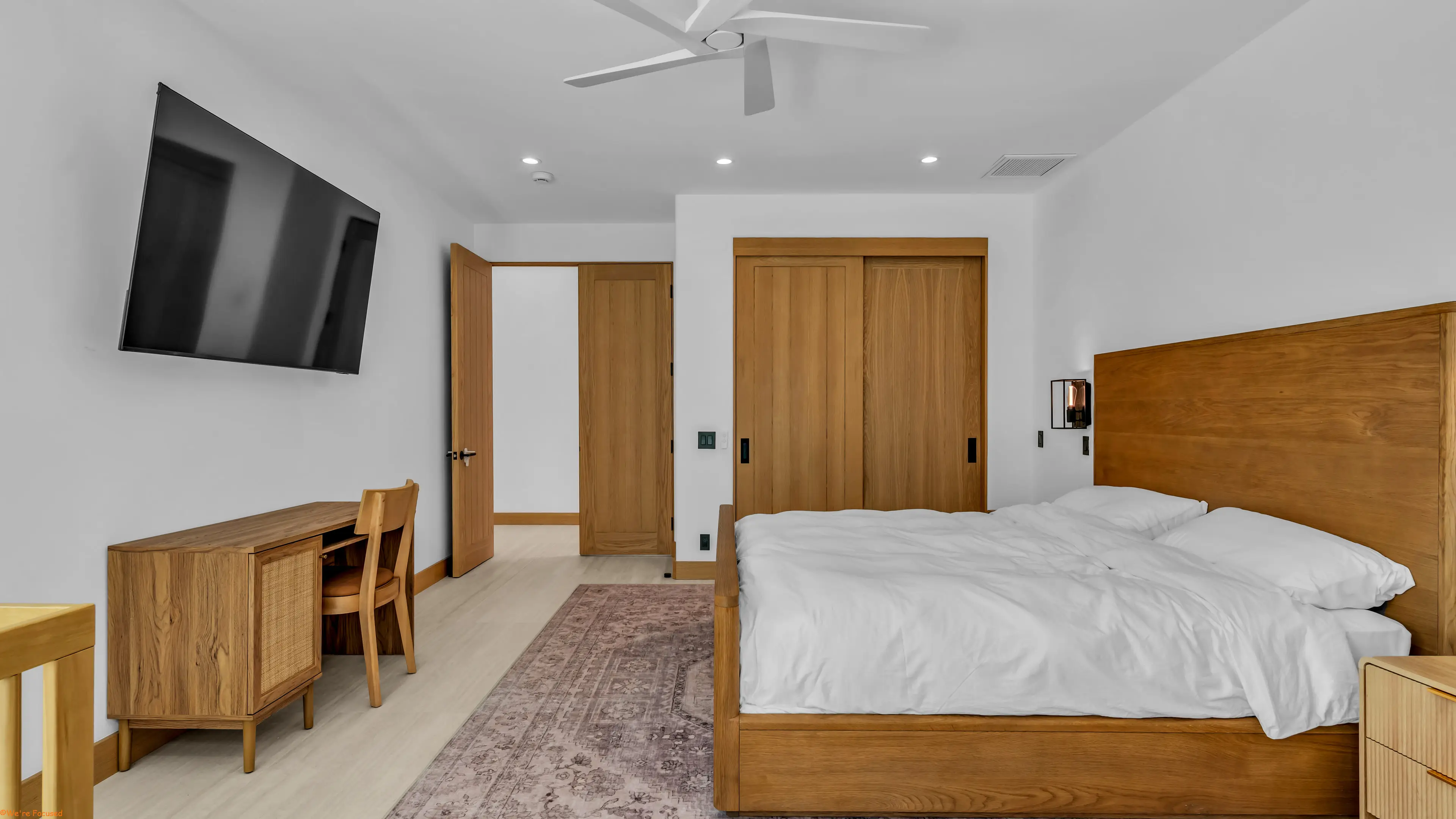 Bedroom with a wood bed frame, a writing desk and a door to the bathroom.