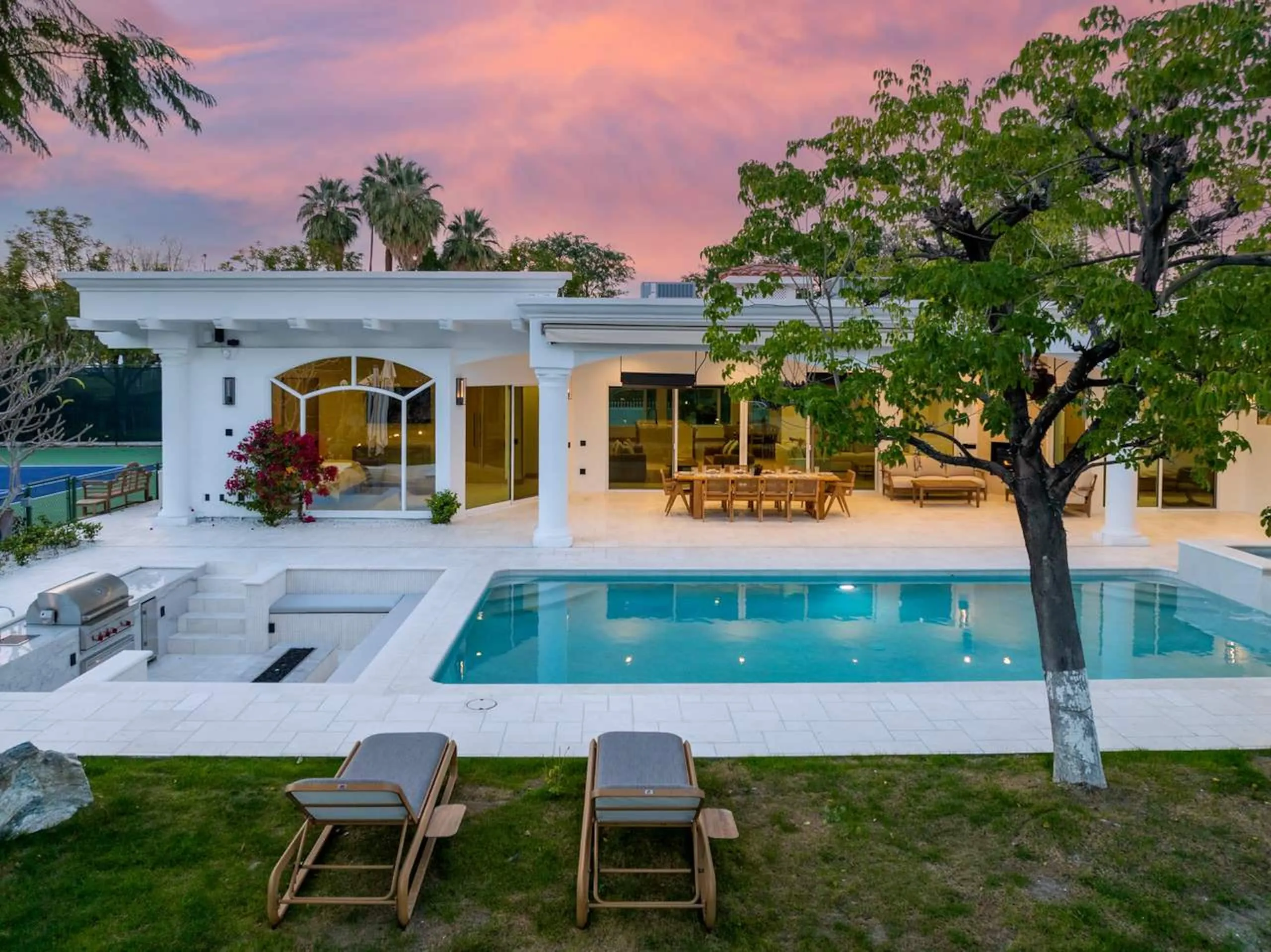 The pool and the house at twilight, bougainvillea in flower and the sky turning pink behind the trees.