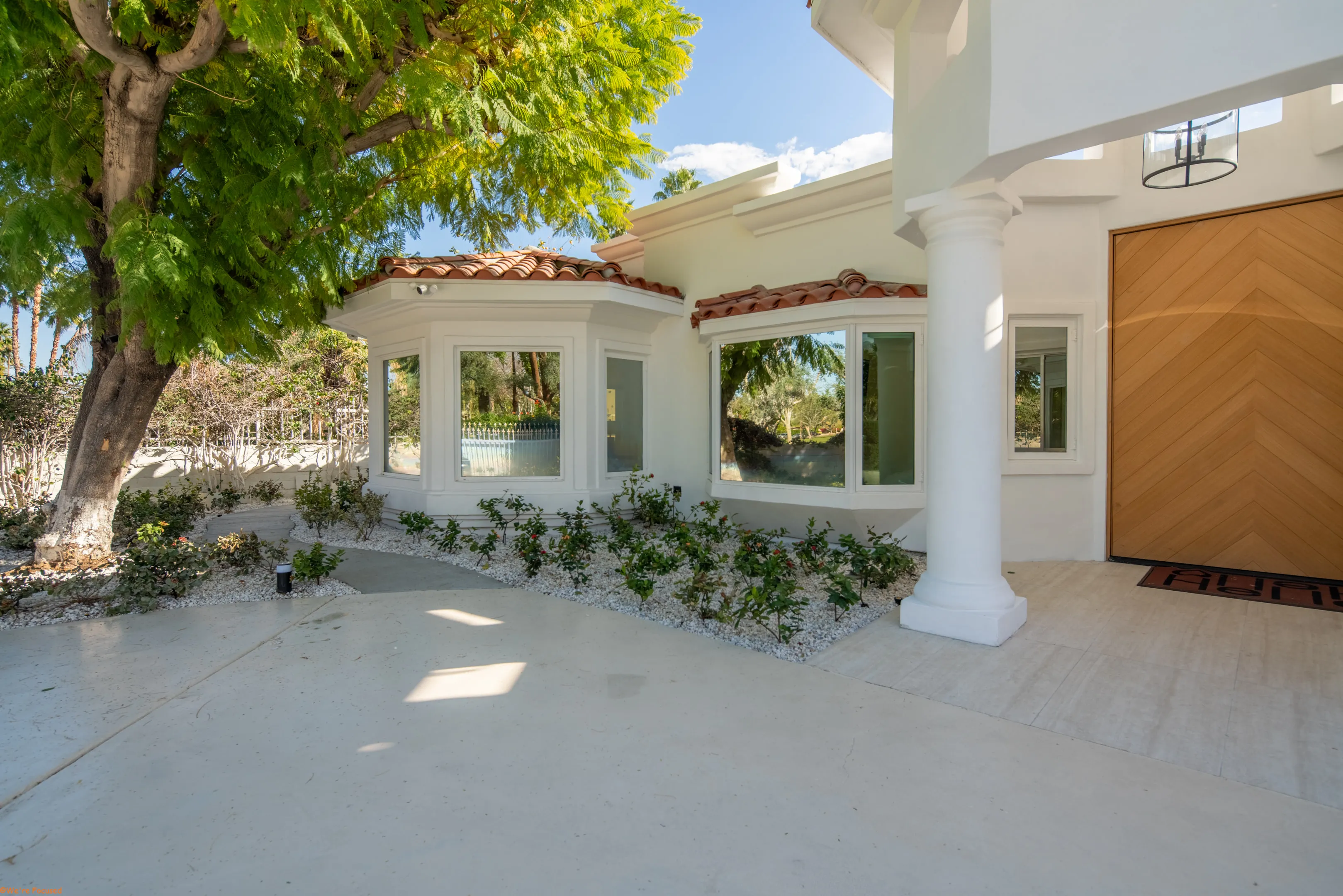 The entrance under the colonnade, the chevron oak door set between white columns.