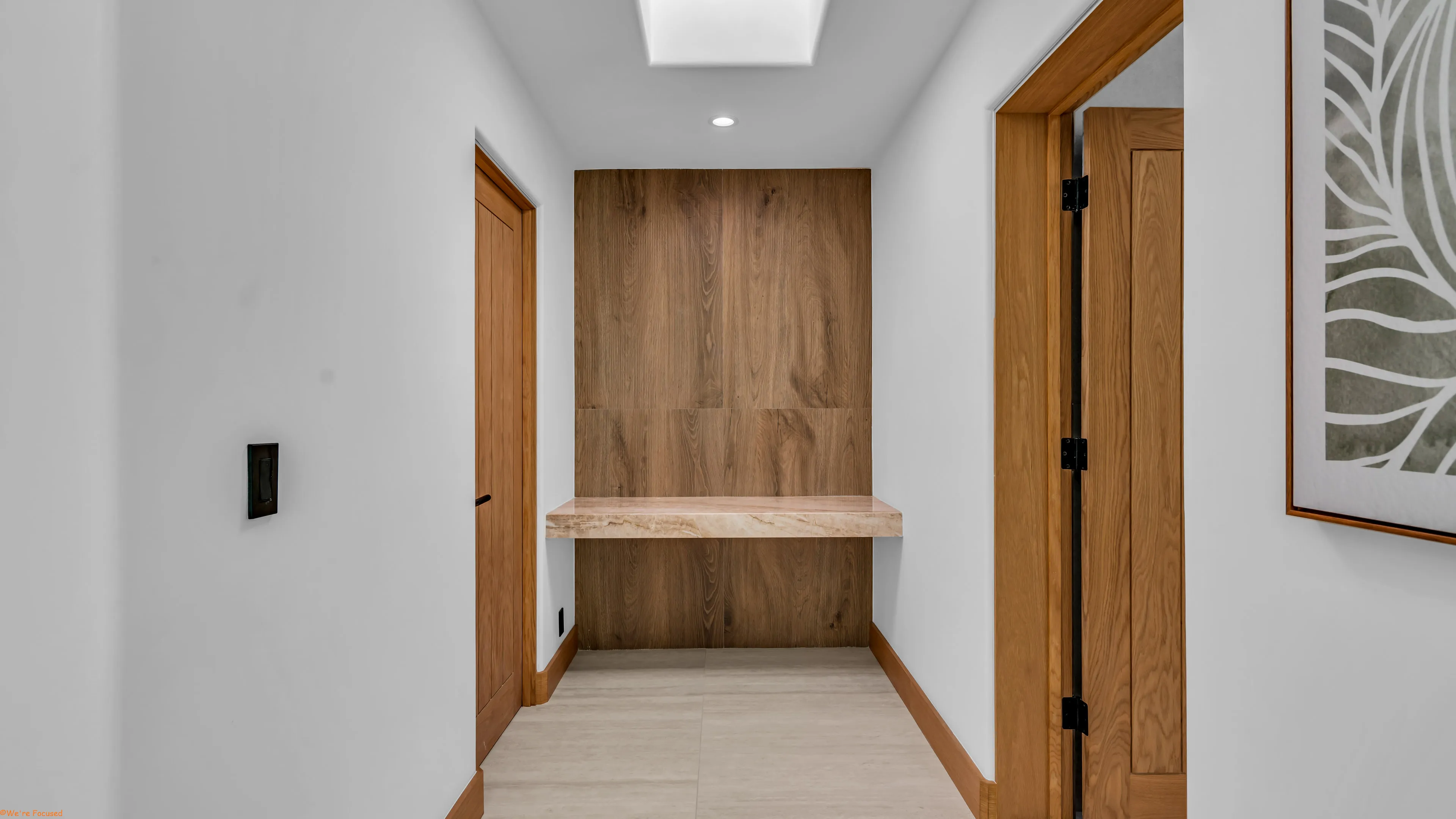 A built in oak bench in a hallway alcove between two doors.