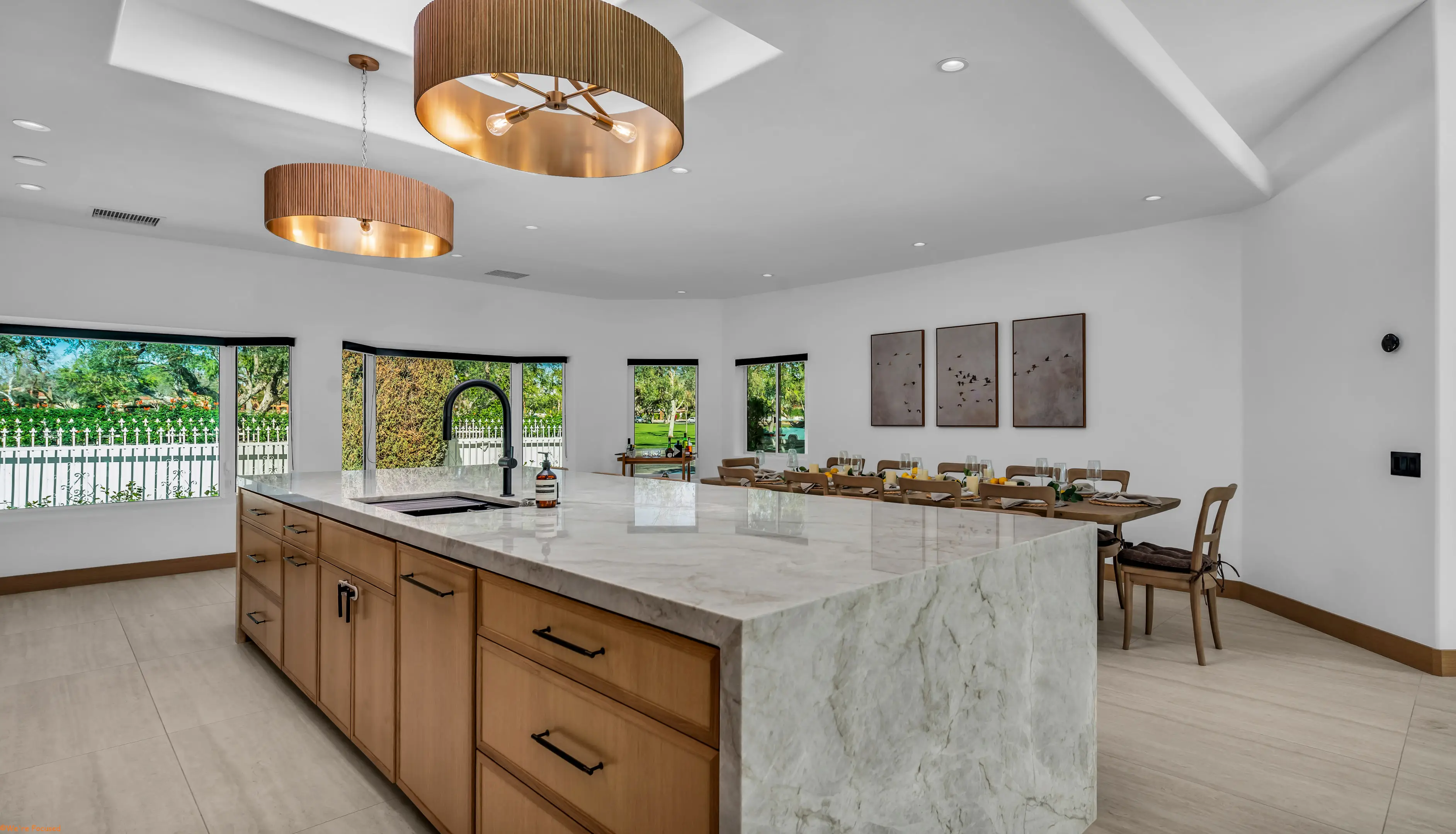 The kitchen island in marble with the dining table and garden windows behind.