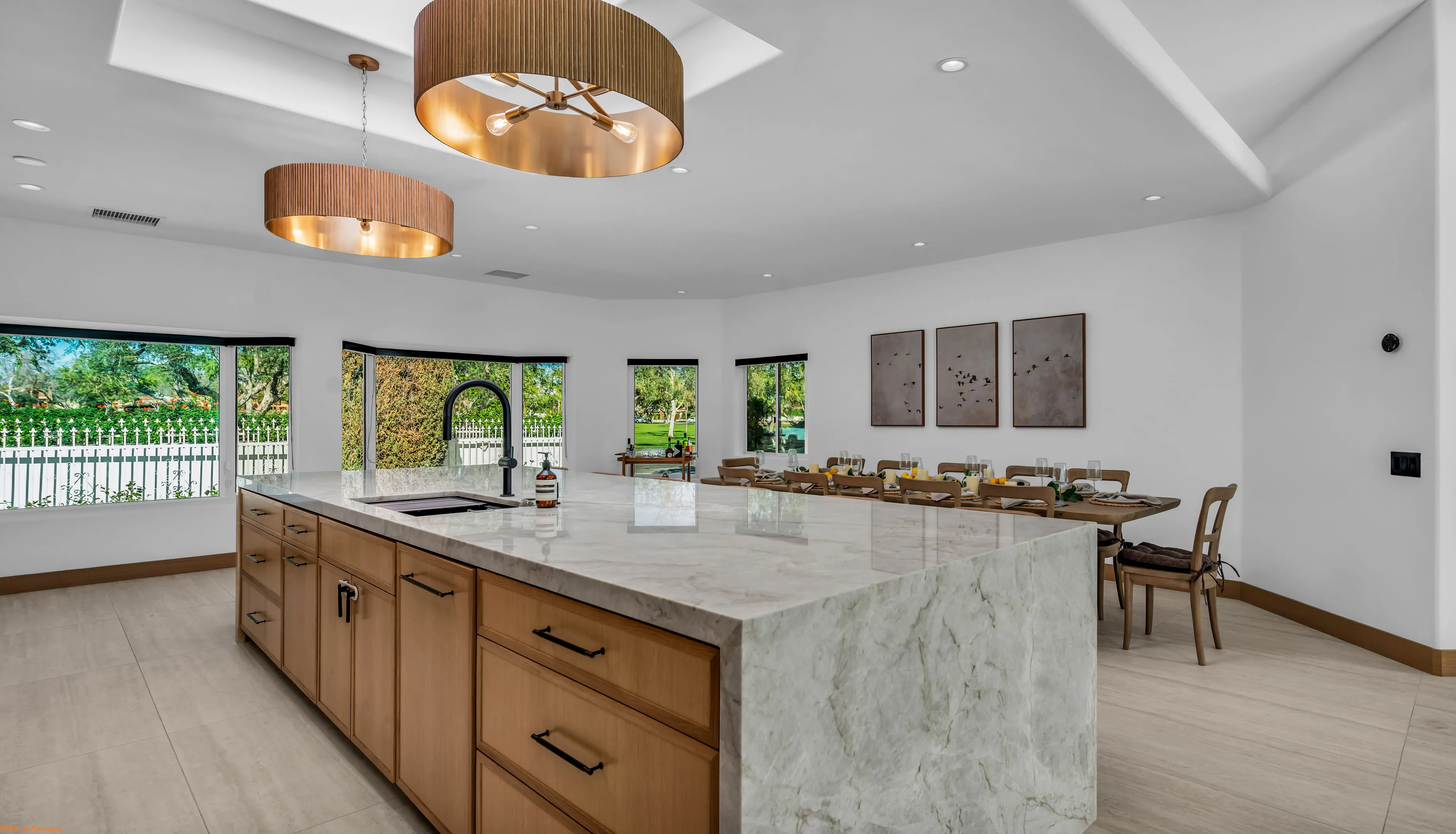 The kitchen island in marble with the dining table and garden windows behind.