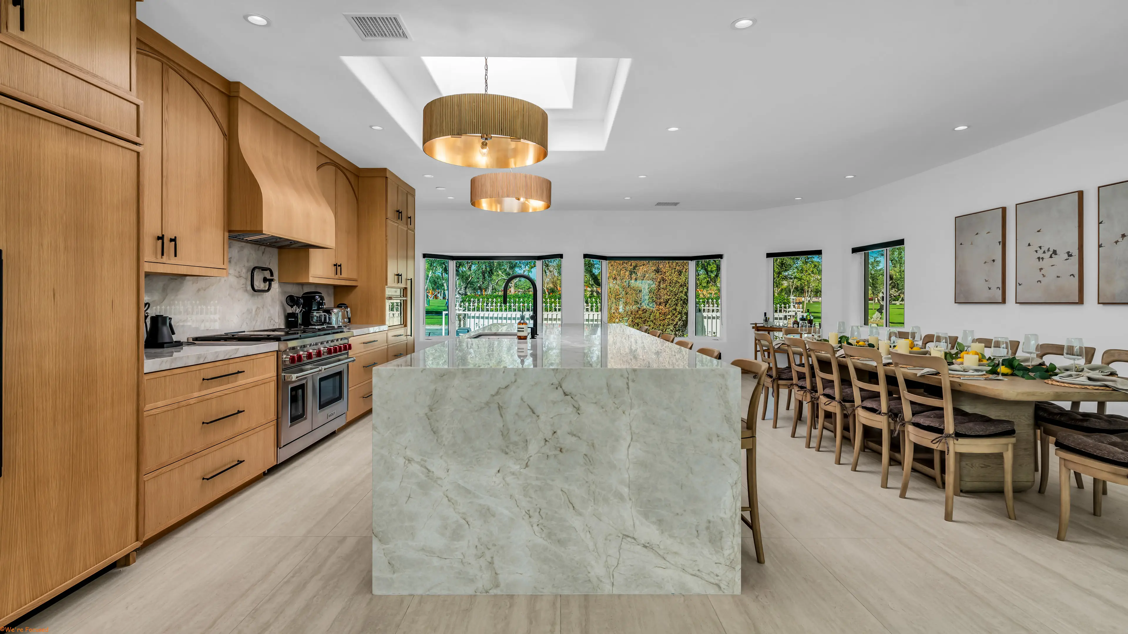 The kitchen with its marble island, oak cabinetry and the long dining table beyond.