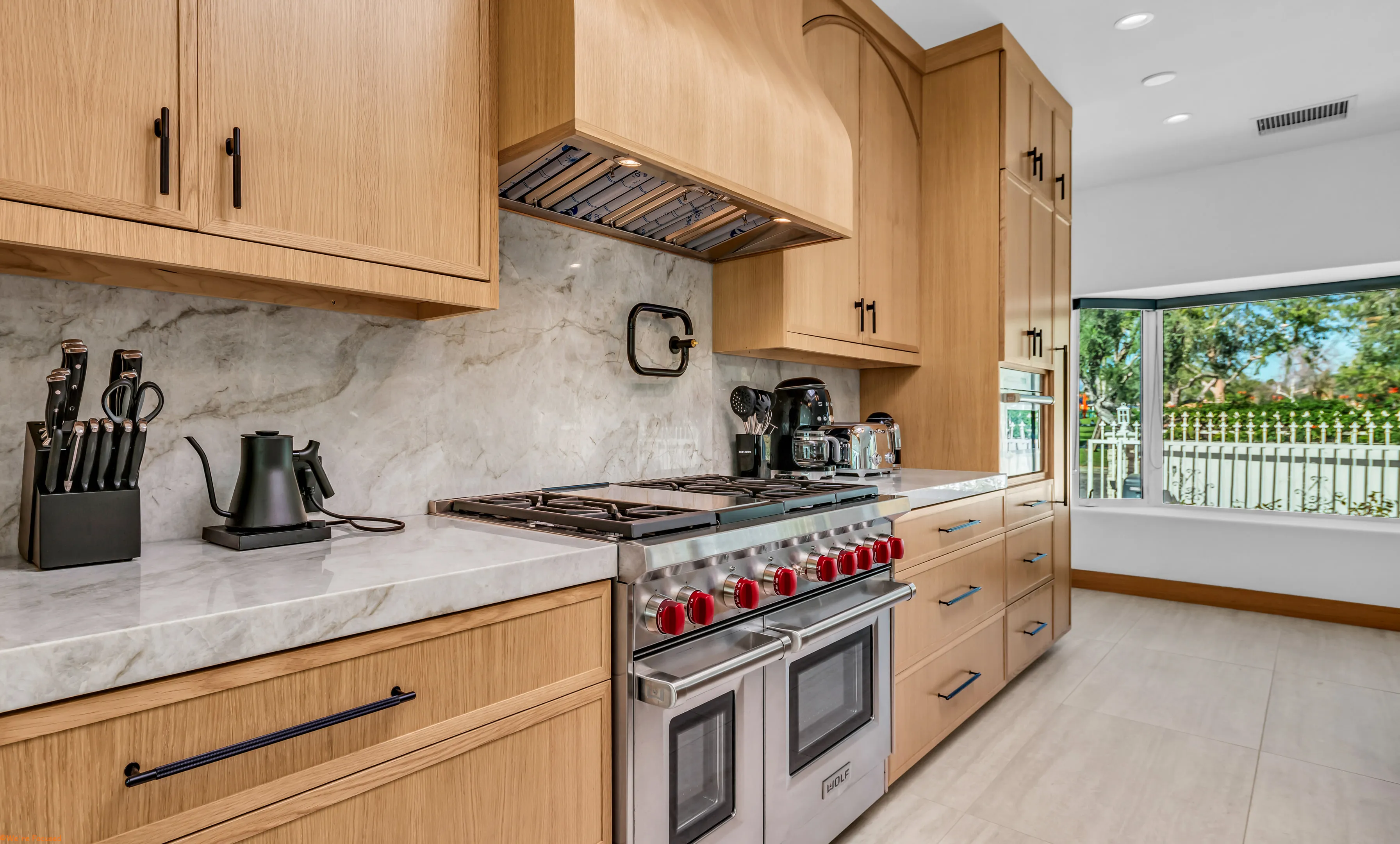 The professional range set into oak cabinetry under a marble hood.