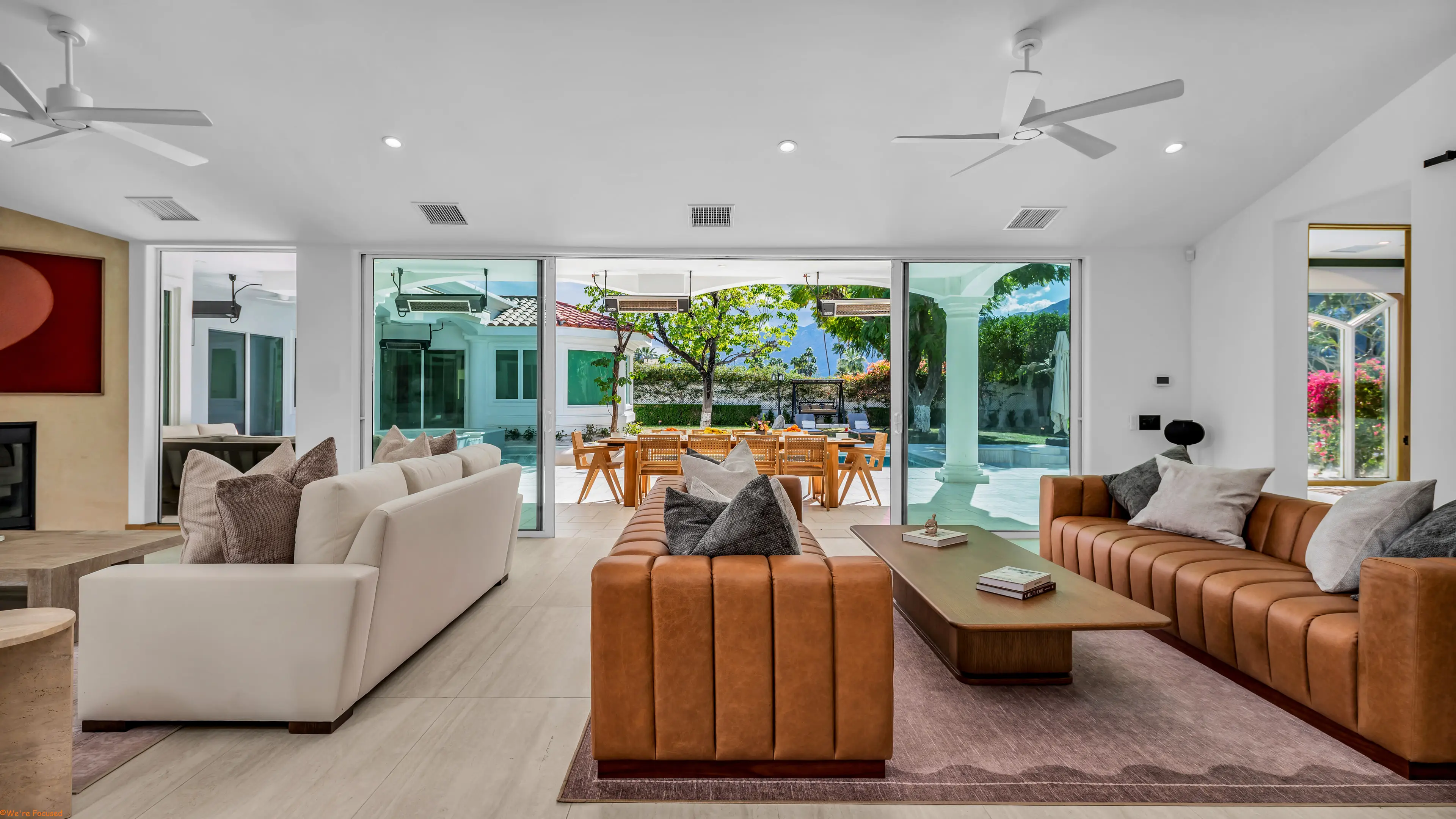 Great room with paired sofas facing the courtyard, the glass wall drawn fully back.