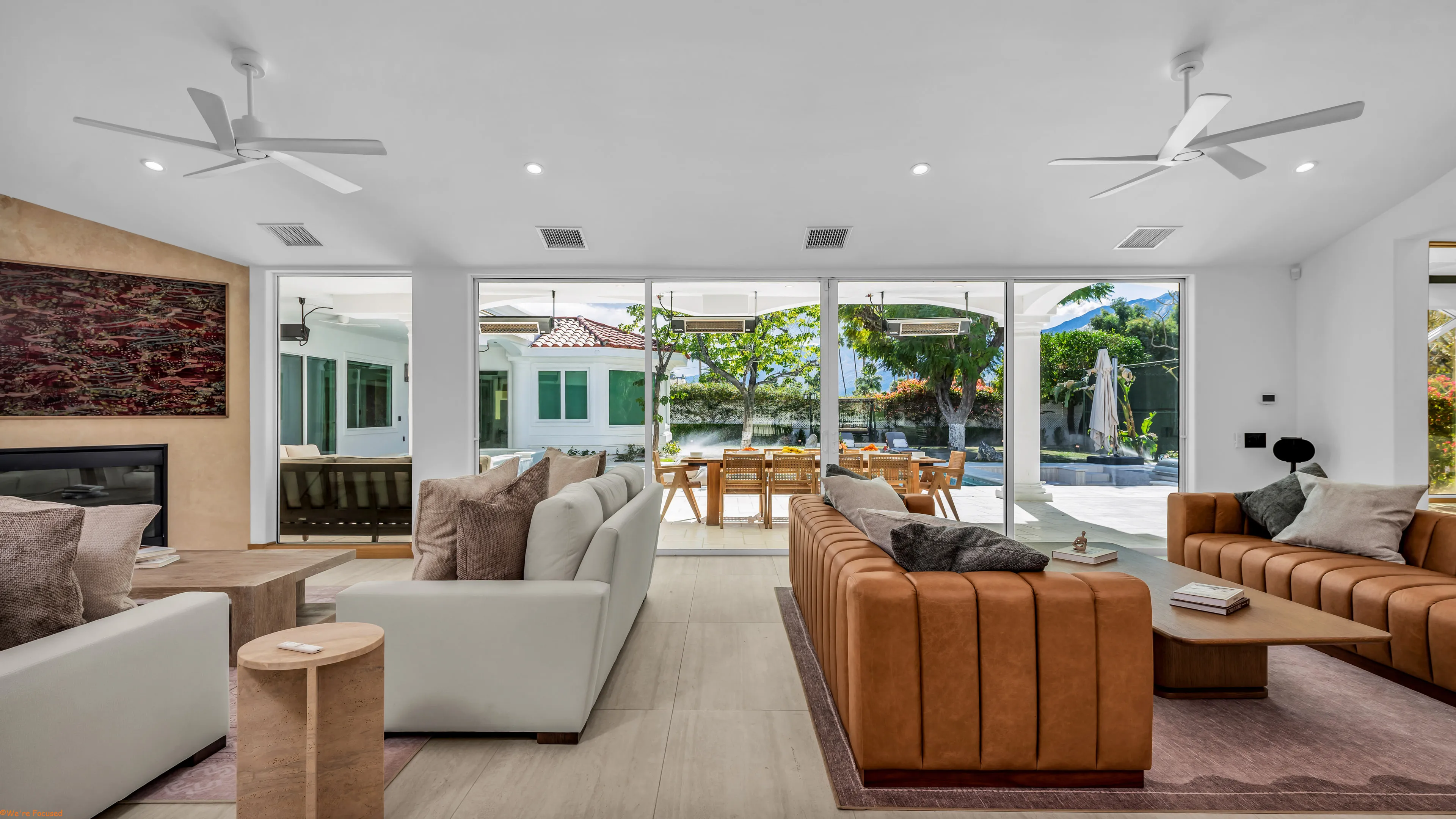 Living room seating with the terrace and pool visible through the open glass wall.