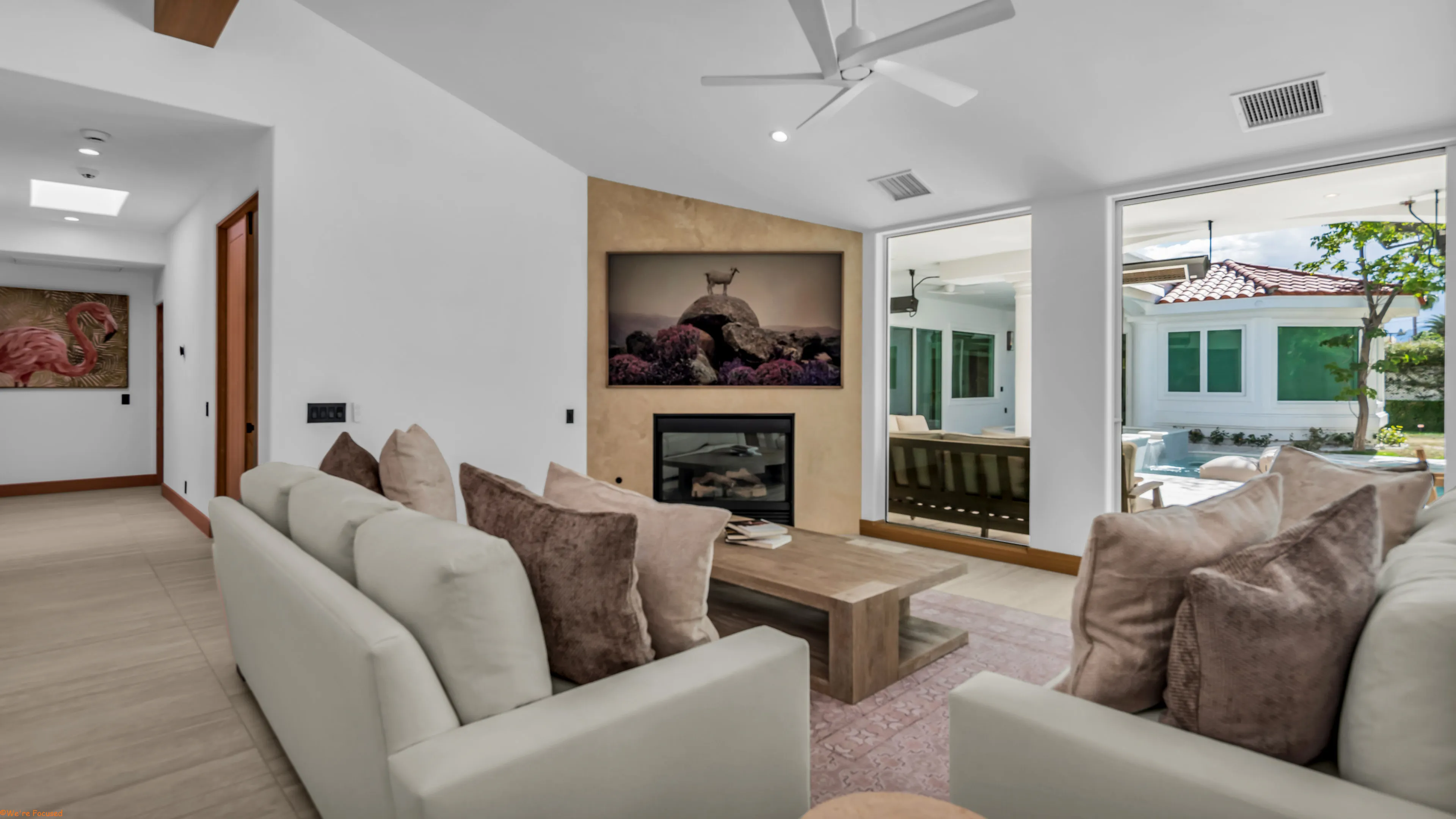 Living room with pale sofas, a stone fireplace and sliding glass onto the terrace.
