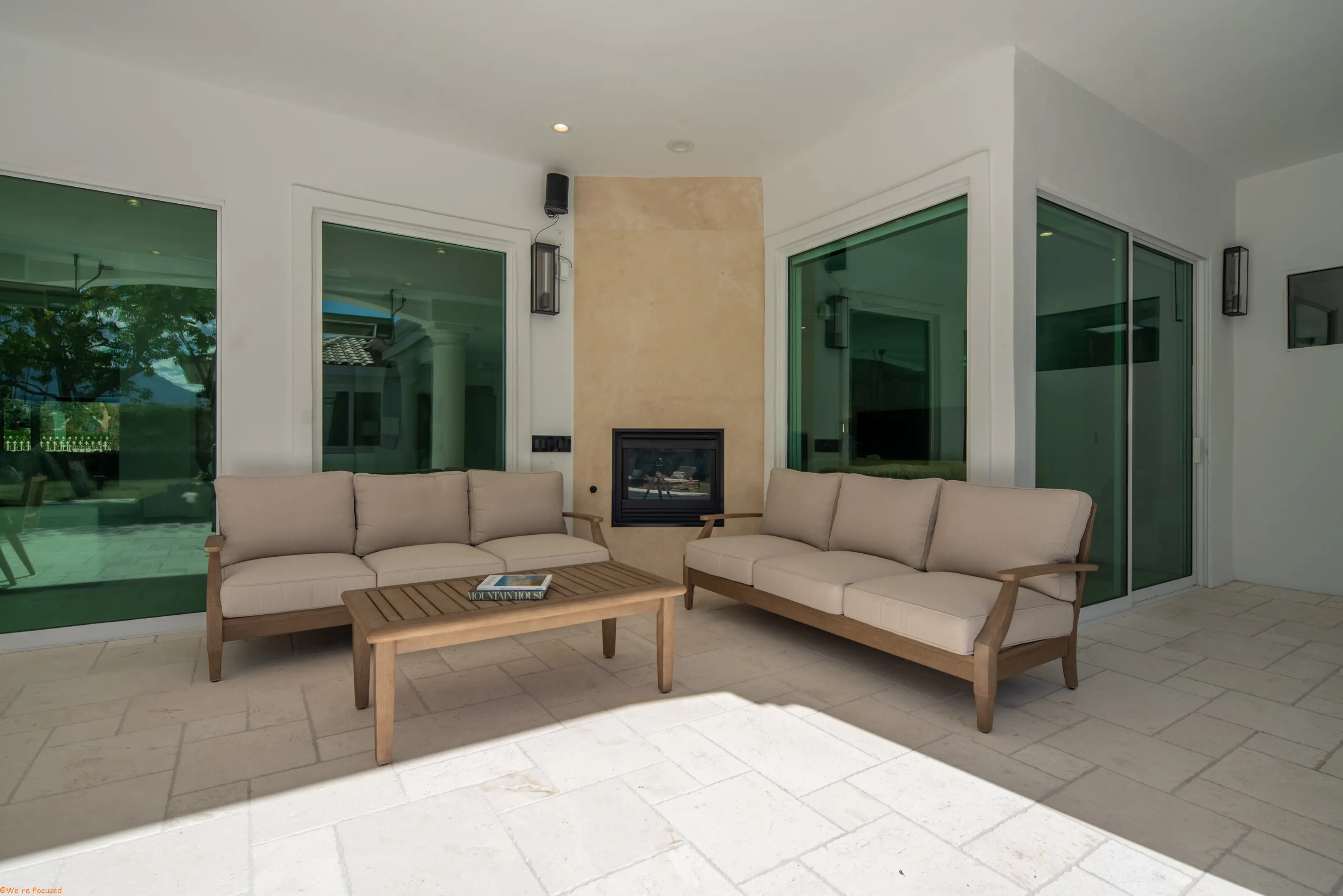 The covered terrace with teak sofas facing an outdoor fireplace set in plaster.