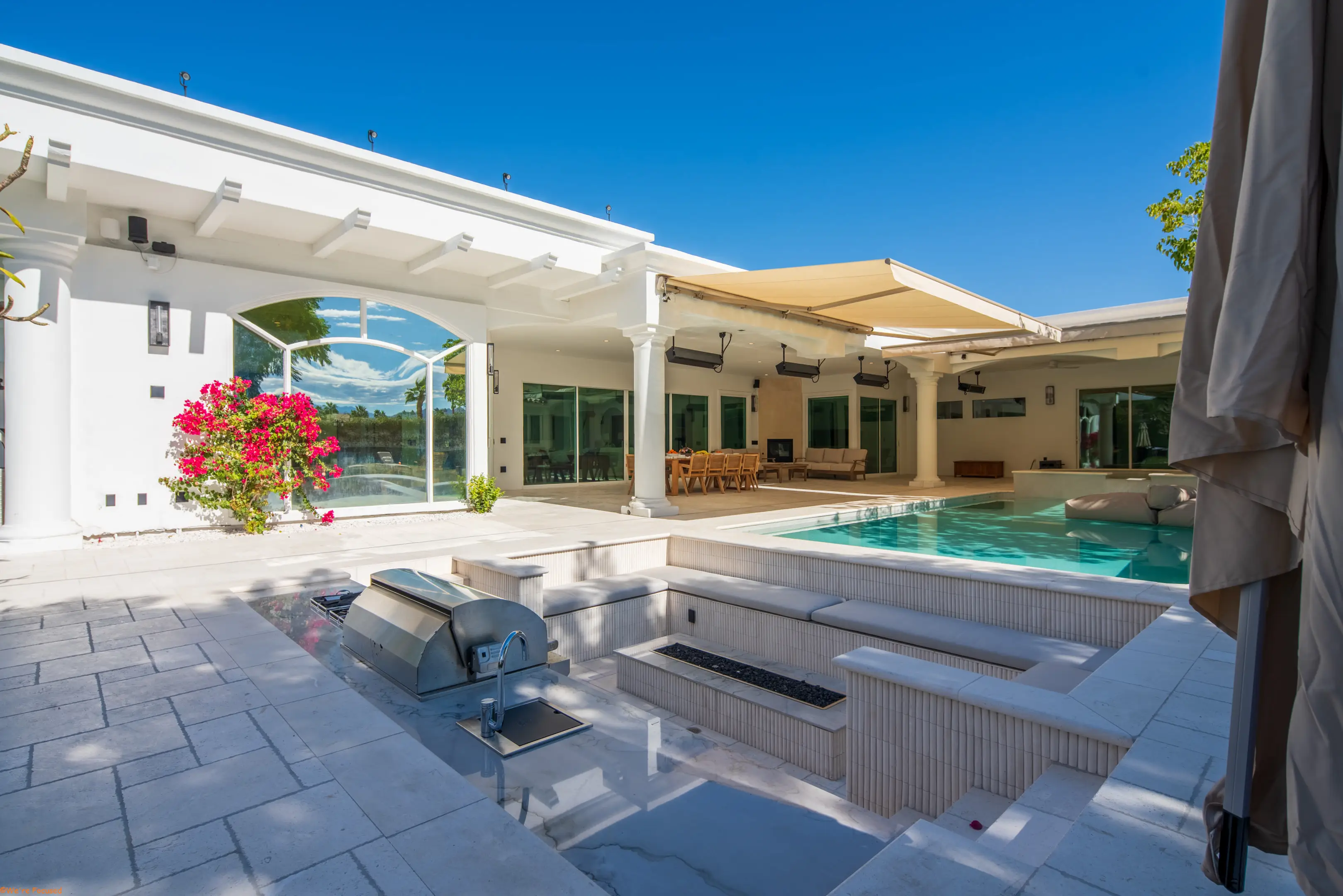 The barbecue and fire pit with the pool and the covered terrace behind.