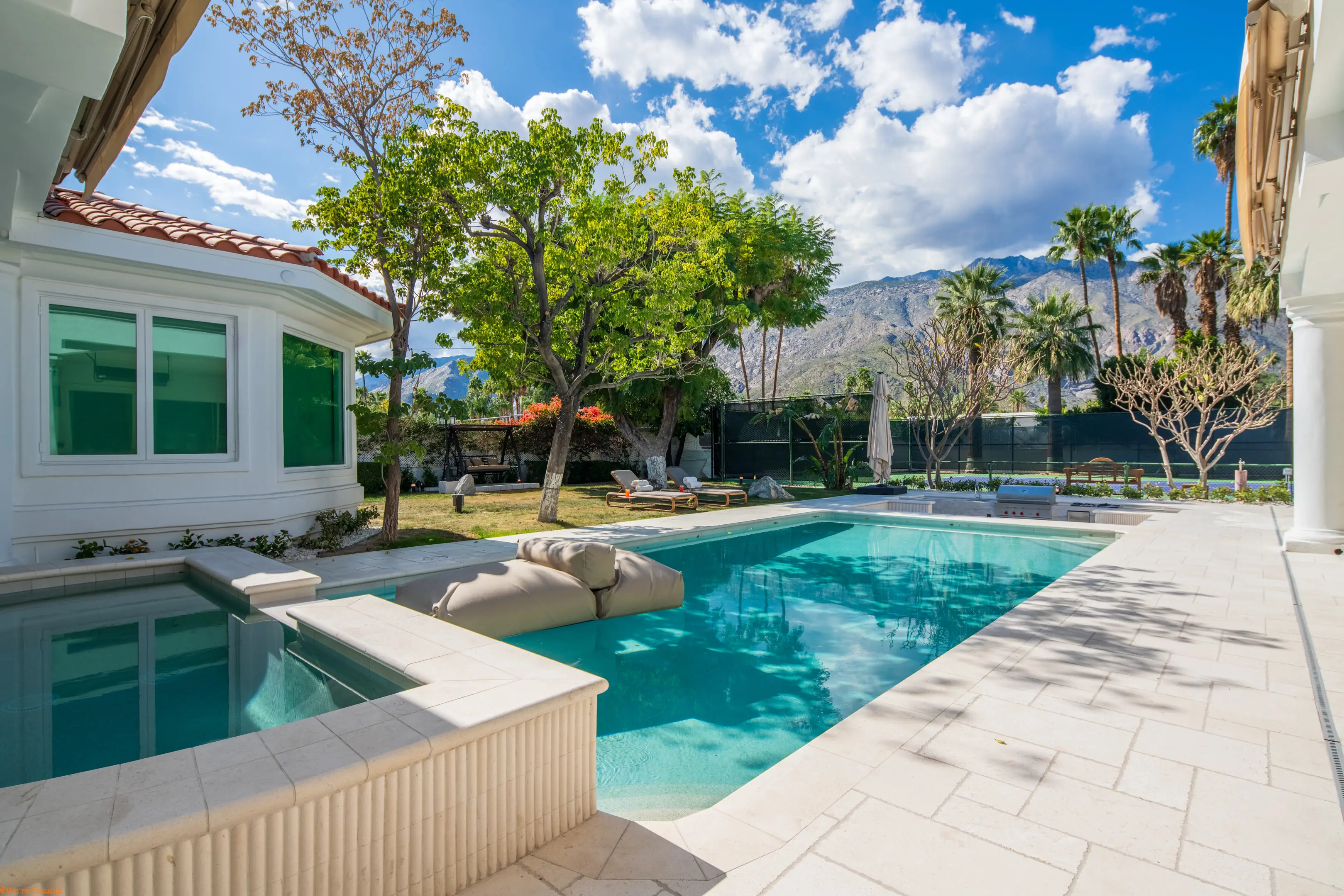 The pool with the lawn, the palms and the mountain ridge behind it.