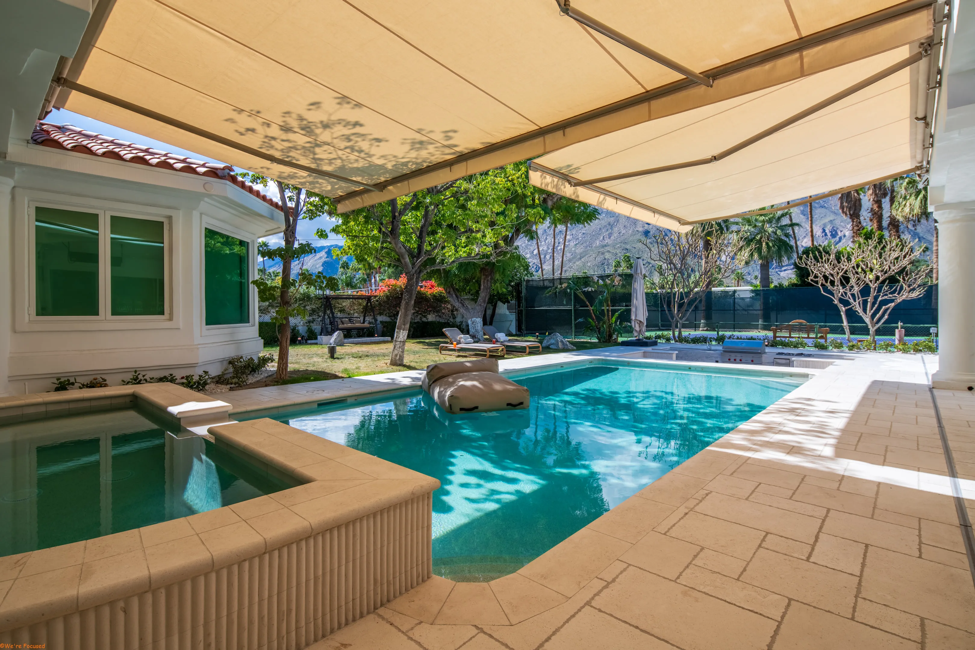 The pool and spa from the shaded terrace, with the house along one side.