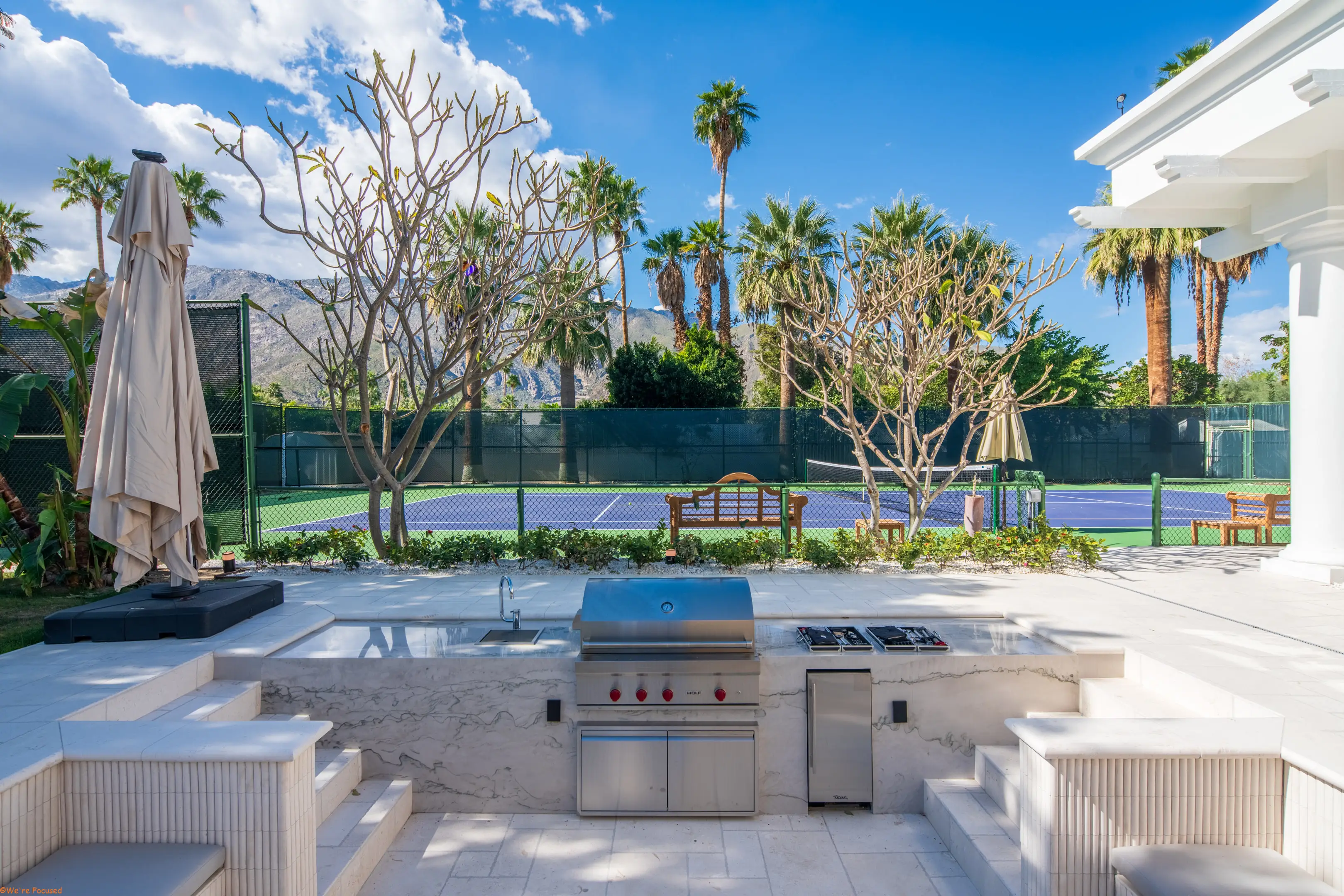The barbecue and fire pit with the tennis court directly behind them.